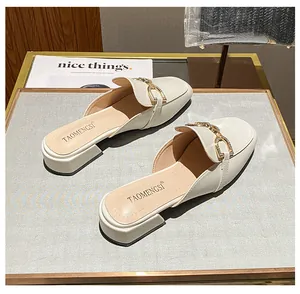 Close-up of cream leather mule shoes featuring a sparkling rhinestone horsebit buckle