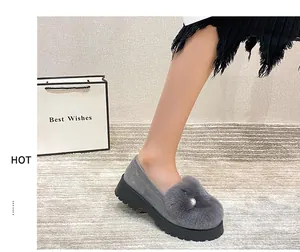 Détail de mocassins en peluche gris avec pompon en fausse fourrure et ornement en perle