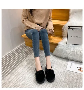 Detailansicht der schwarzen Damen-Plüsch-Loafer mit Hasenohren auf einer Holztreppe
