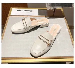 Detalle de mules blanco crema de punta cuadrada con perla y barra de metal dorado