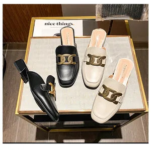 Detailansicht von Leder-Mules mit goldener Kettenschnalle auf einem schicken Display