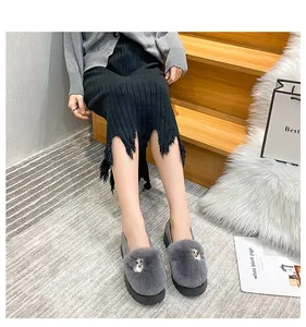 Detail of dark grey plush loafers featuring a metallic fox buckle and thick black soles