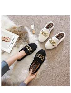 Detail of plush faux fur slippers with gold metal chain buckles in black and white