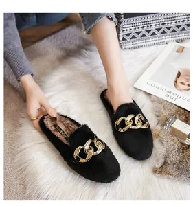 Detail of plush black mule slipper featuring a large gold chain link and fuzzy texture