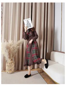 Detail of a brown long sleeve dress with plaid stitching and ruffled layers