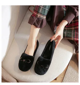 Detailed close-up of black faux fur loafers with gold bow ornament and plush interior