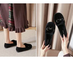Detail of plush black loafers with rabbit fur trim and a decorative golden bow buckle