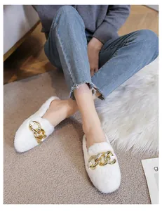 Detailed view of white faux fur loafers with a prominent gold chain link buckle on top