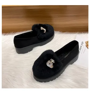 Detail of black suede loafers featuring plush faux fur and a crystal fox ornament