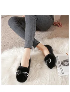 Dettaglio delle ballerine in peluche nero con fiocco di perle e calda pelliccia finta
