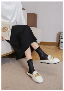 Close-up of plush faux fur slippers with gold buckle detail on a model in indoor setting