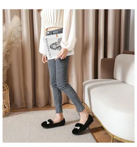 Gros plan de mocassins en daim noir avec pompons en fourrure et boucles en strass brillants