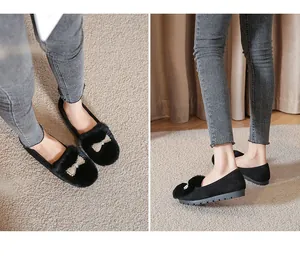 Détail de ballerines noires en daim pour femmes avec bordure en fourrure et nœud perlé