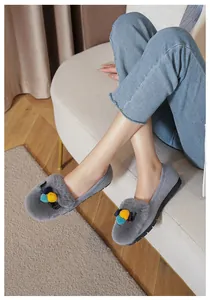 Dettaglio di mocassini in peluche grigio con pompon colorati e decorazione a fiocco nero