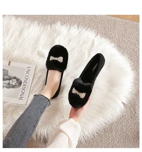 Gros plan sur les chaussures plates en peluche noire avec nœud perlé et fausse fourrure