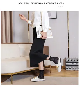 Detail of white faux fur loafers featuring a bold gold chain link and non-slip black sole