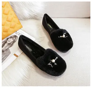 Detail van zwarte loafers van imitatiebont met fonkelende stergesp en een grote parel