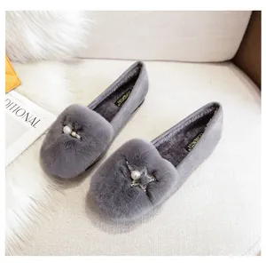 Detail van zachte konijnenvacht voering en parelster bedeltjes op grijze loafers