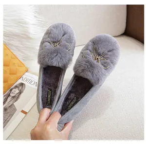Close-up of grey plush loafers with faux rabbit fur trim and golden leaf jewelry detail