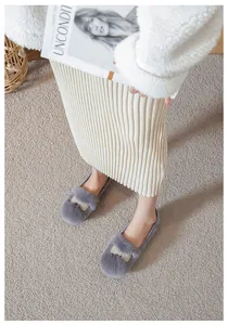 Gros plan de chaussures plates en peluche grise avec décoration de nœud en perles