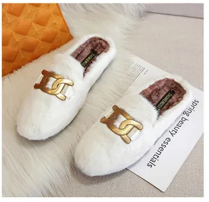 Detailed close-up of white plush mules featuring a stylish matte gold chain ornament
