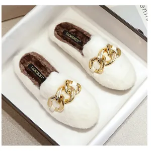 Detail of white faux fur mule with a large gold buckle and plush dark brown lining