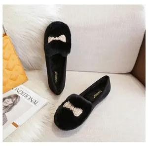Détail de mocassins en peluche noire avec nœud en perles et doublure chaude en fourrure