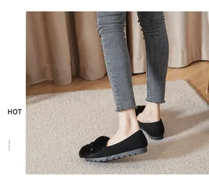 Detail van zwarte suède platte schoenen met bontballen en een antislipzool voor dames