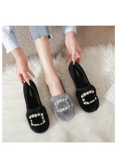 Primer plano de mocasines de felpa con hebillas de perlas en negro y gris de invierno