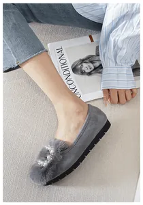 Detalle de mocasines de ante gris con pompón de pelo y adorno de corazón de perla