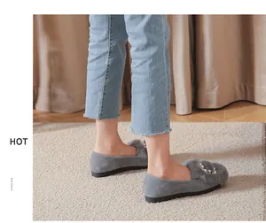 Detalle de mocasines de ante gris con ribete de piel de conejo y perlas sobre jeans