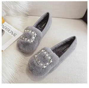 Detalle de mocasines de felpa gris con elegante hebilla cuadrada de perlas y strass