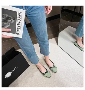 Top view of light green leather ballet flats with black bow detail on a model