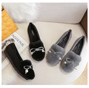 Detail of winter loafers featuring decorative fur balls, pearls, and rhinestones