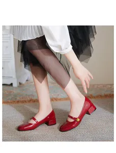 Detail of red patent leather Mary Jane shoes with decorative gold flower buckle