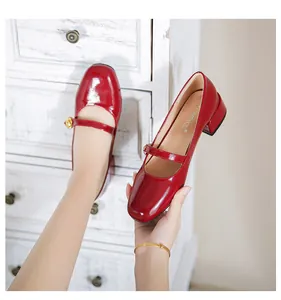 Close-up of red patent leather Mary Jane shoe with gold spherical button and low block heel