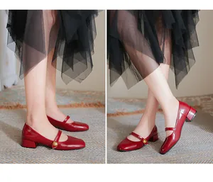 Detailed view of red patent leather Mary Jane shoes with vintage gold metal buckles