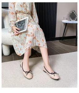 Detail of beige ballet flats featuring black trim and a delicate bow tie on square toe