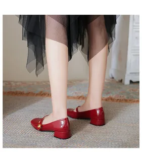 Close-up of red patent leather Mary Jane shoes with low block heels and gold buttons