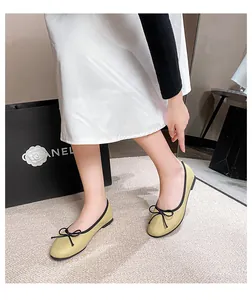 Side view of beige ballet flats with black bow detail and leather texture on a woman