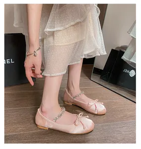 Close-up of pink satin ballet flats with rhinestone strap and delicate bow detail