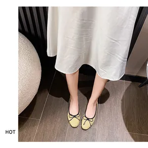 On-foot view of pale yellow ballet flats with black ribbon bow and contrasting trim