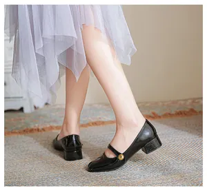 Detailed view of black patent leather Mary Jane shoes with vintage gold buckle on model