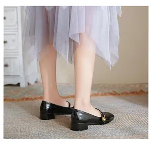 Detail of black patent leather Mary Jane shoe with gold buckle and block heel