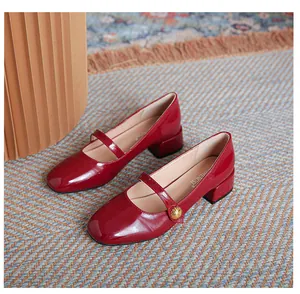 Close-up of deep red patent leather Mary Jane shoes with vintage gold buckle on blue carpet
