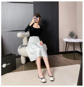 Black ribbed knit top paired with white satin midi skirt and cream bow ballet flats