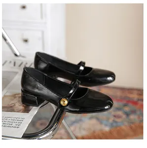 Detail of black patent leather Mary Jane shoe with gold daisy buckle on a vintage book