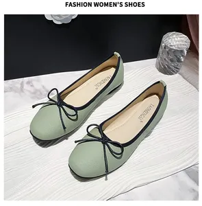 Close-up of light green ballet flats with black bow detail and textured faux leather finish