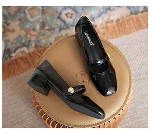 Detail shot of black patent leather Mary Jane shoes with gold buckle on a brown pedestal