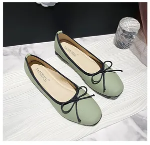 Close-up of light green ballet flats with litchi texture, black trim and a bow detail
